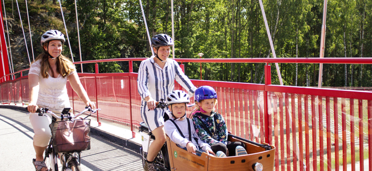 Två cyklister som cyklar över den röda bron i Åtvidaberg